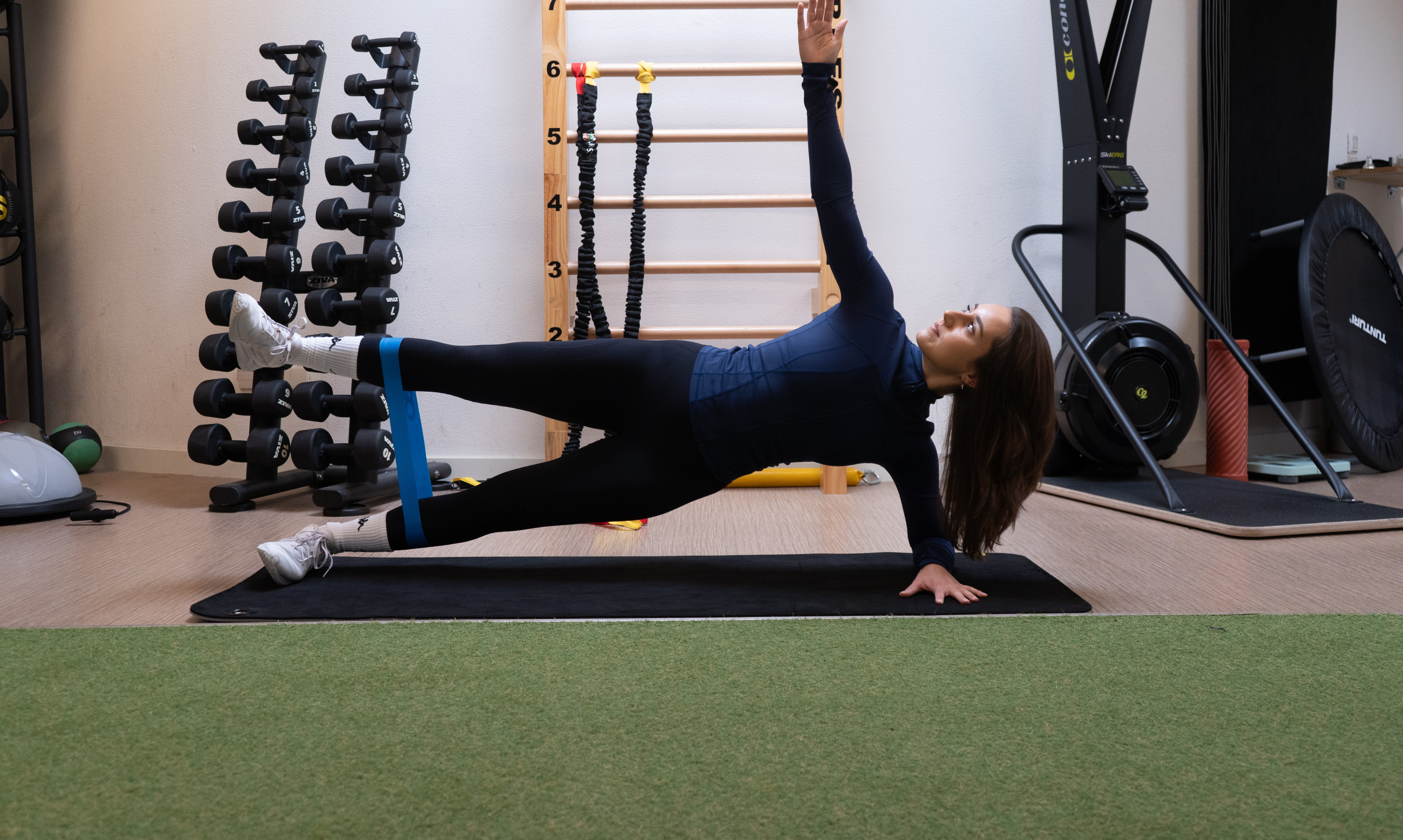 Nina doet een oefening met een elastiek op een yogamat.